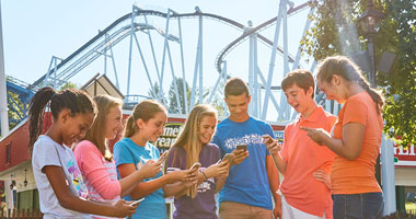 Kids using Hersheypark app next to Great Bear rollercoaster