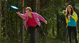 woman throwing a disc at Disc Golf Course