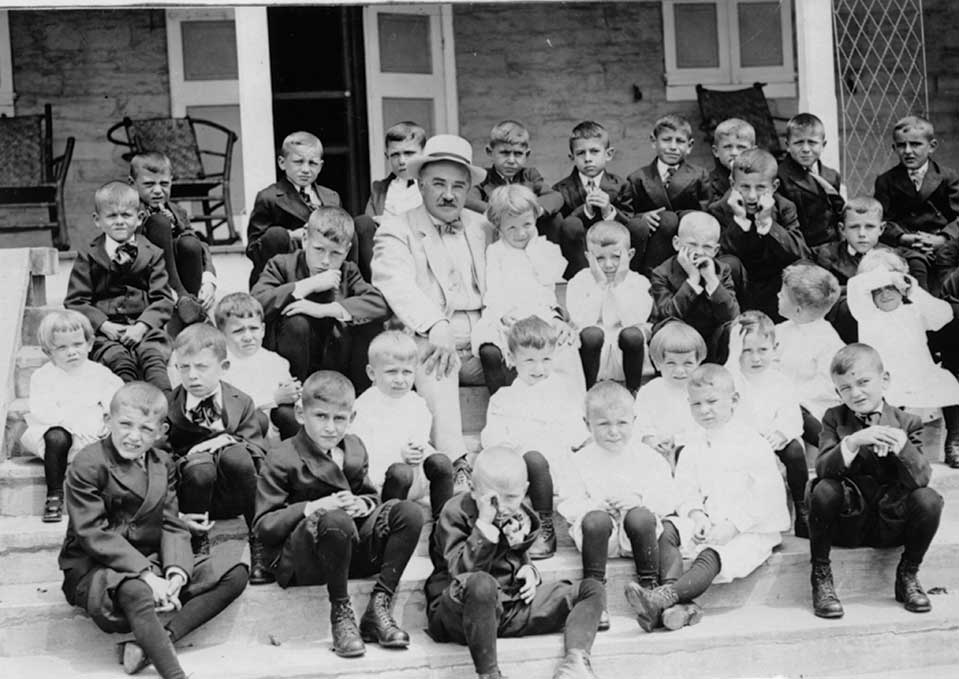 Milton Hershey on the steps with boys from the Milton Hershey School