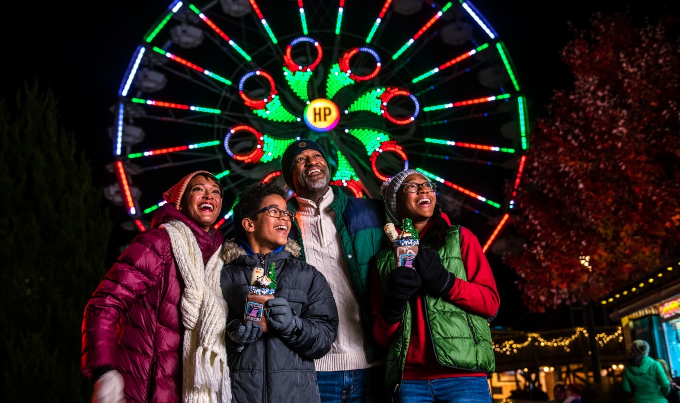 Family in front of ferris wheel at Hersheypark Christmas Candylane in Hershey PA