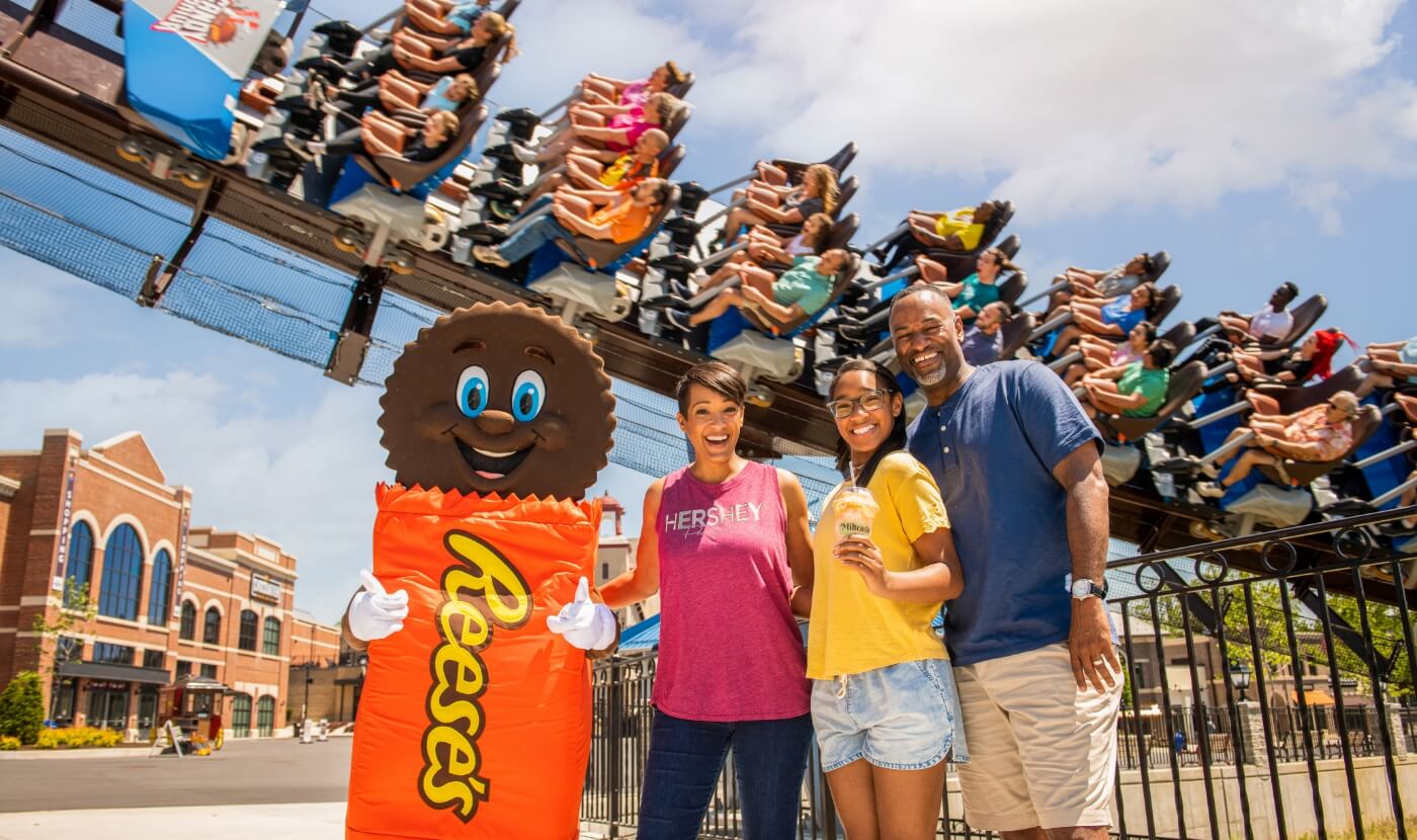 Family in front of Candymonium roller coaster at Hersheypark with Reese's character