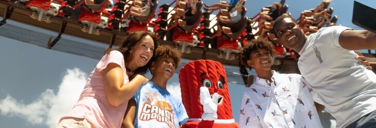 Twizzler character with family at Hersheypark with Candymonium roller coaster in background